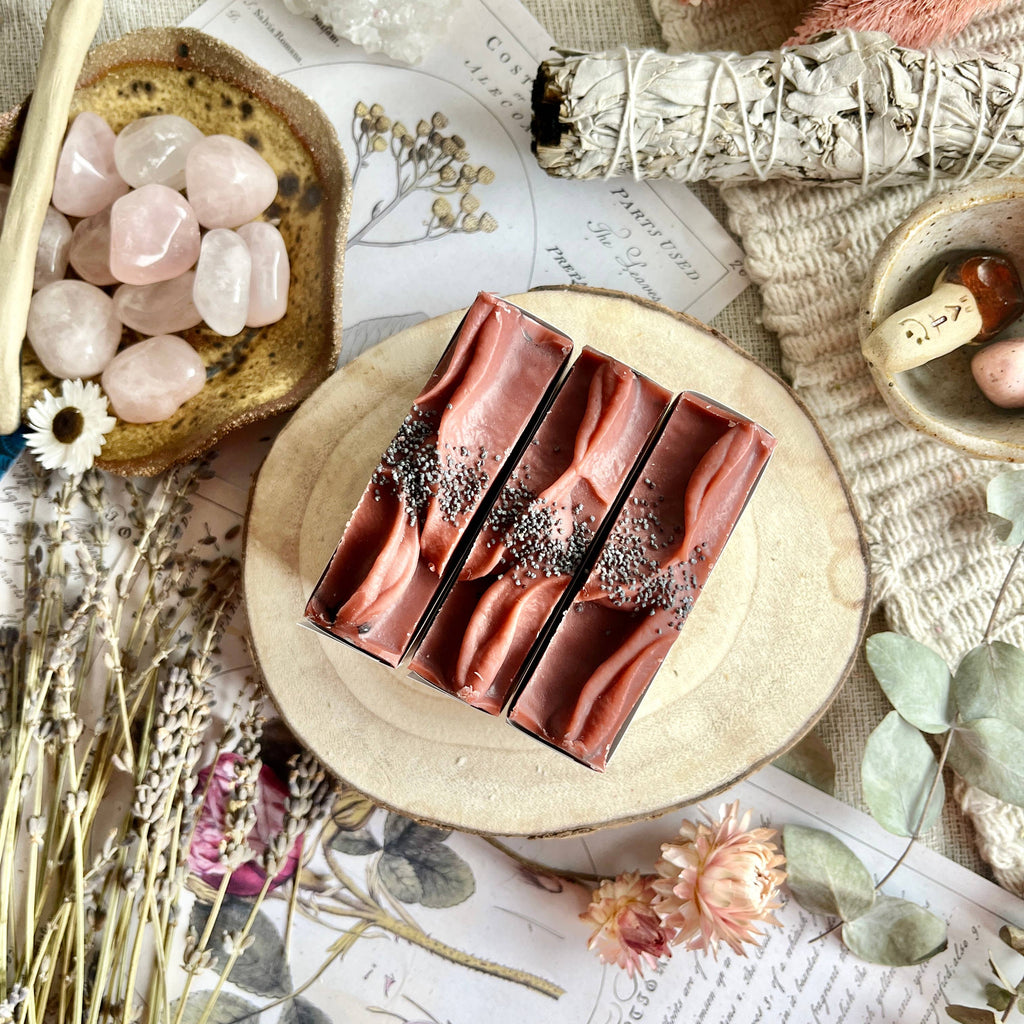 Red soap bars on a wooden board with decorative elements like flowers and crystals.