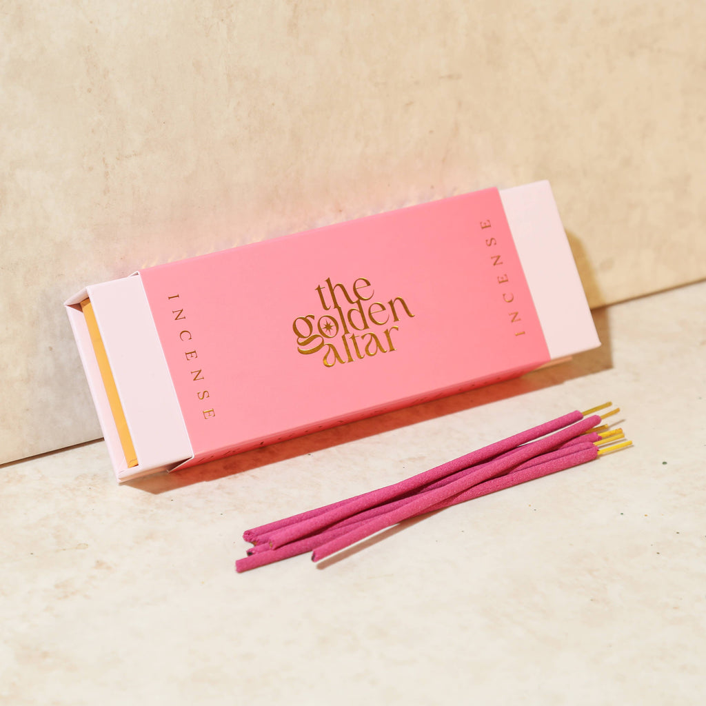Pink incense box with 'the golden altar' branding and pink incense sticks on a beige background